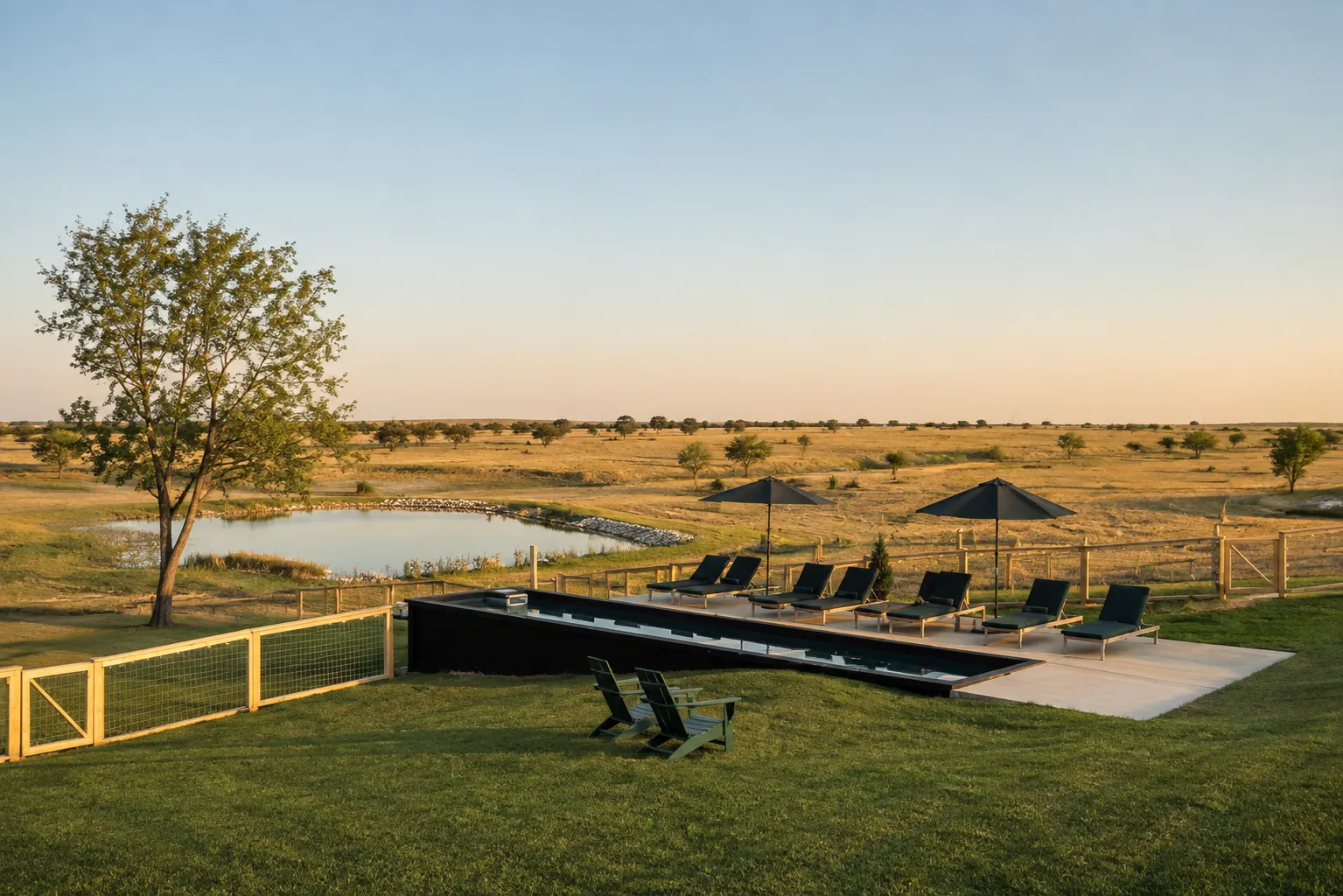 Black container lap pool beside a ranch pond at golden hour